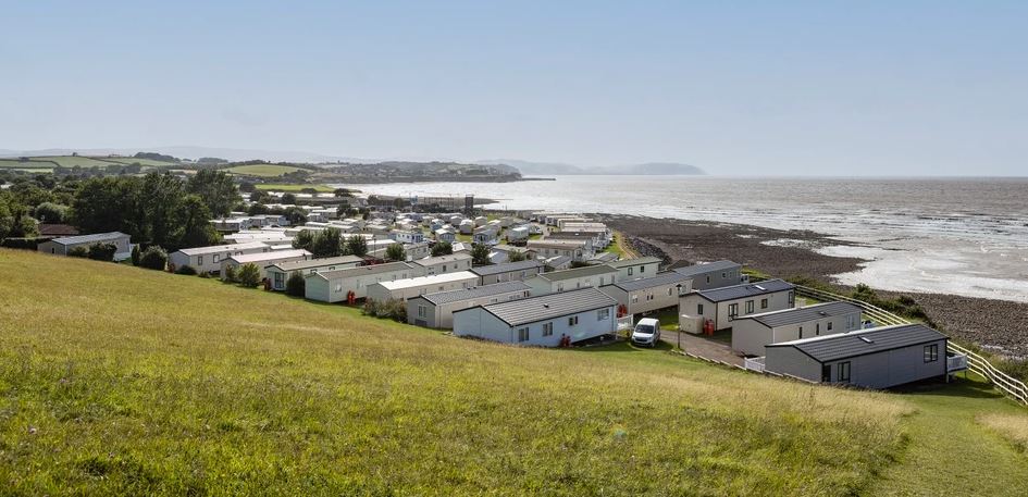 A view of holiday homes from the green field above with the ocean in the backgound