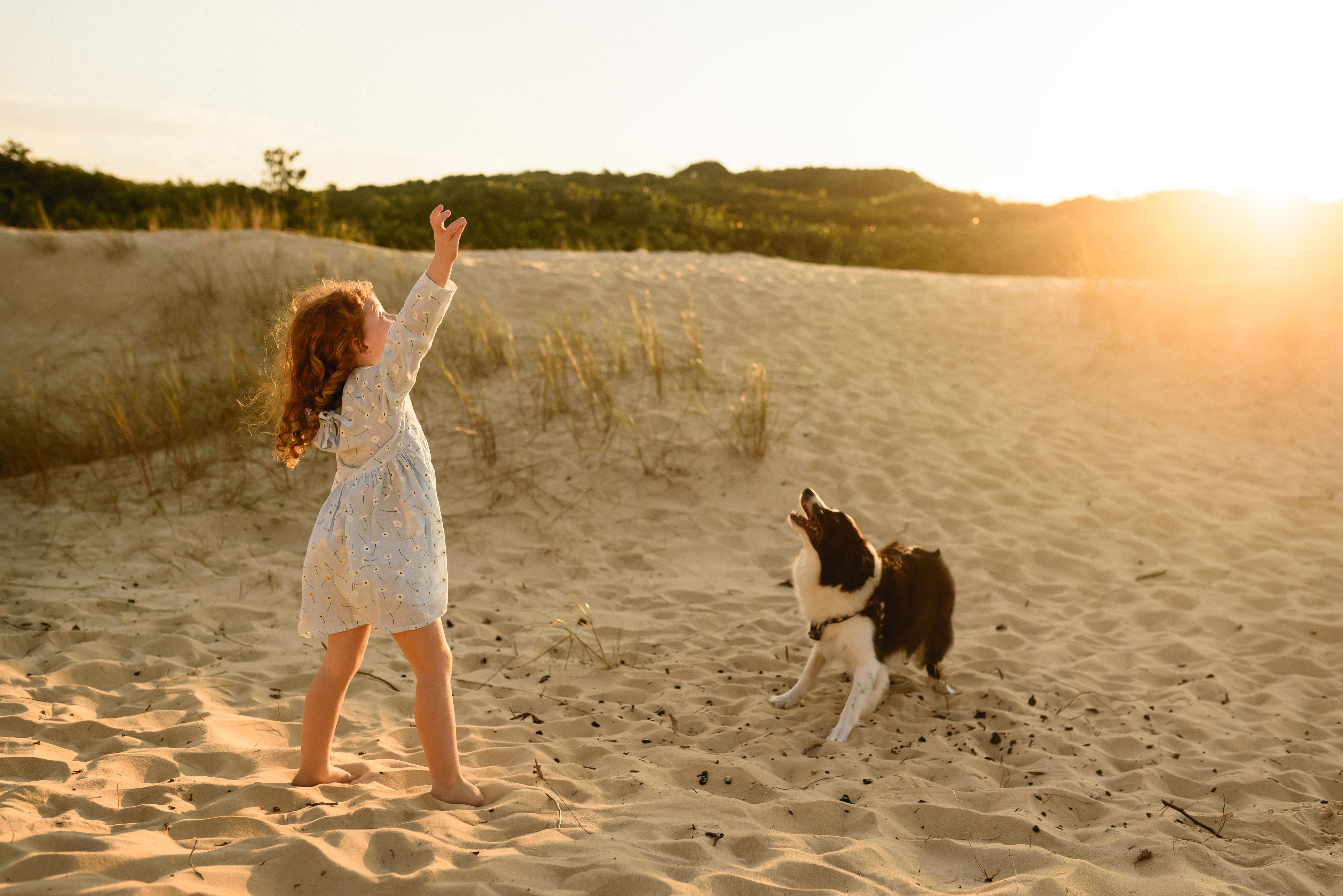 A girl playing with her dog in the sand dunes