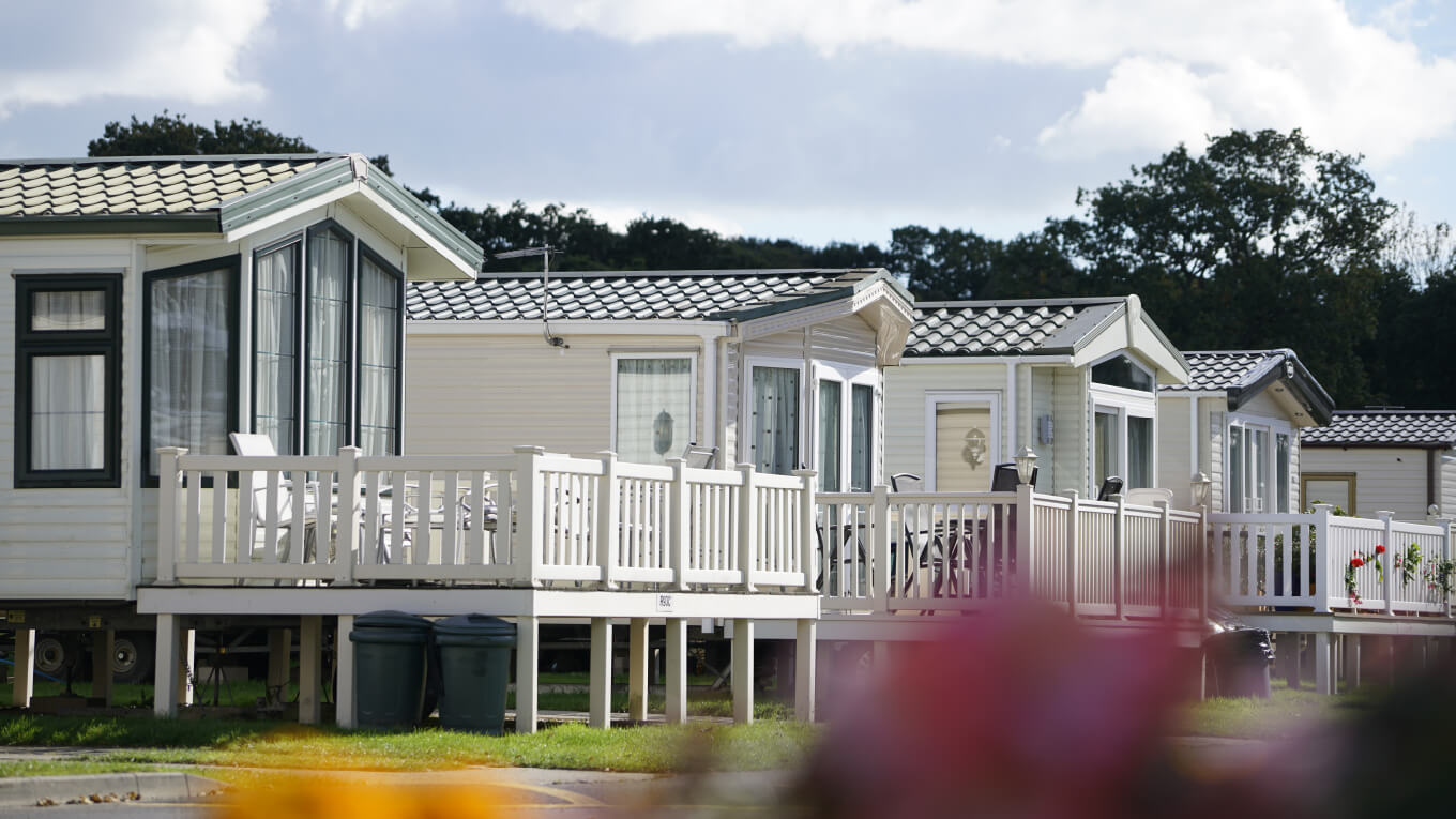 A row of holiday homes surrounded by woodland and flower gardens