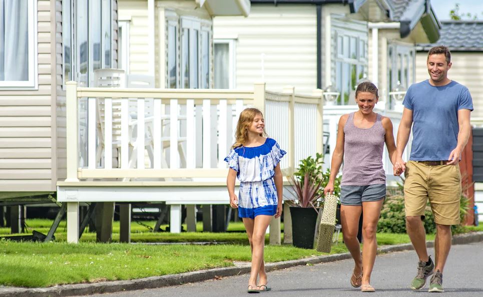 A family walking through a holiday park past holiday homes on a warm summers day