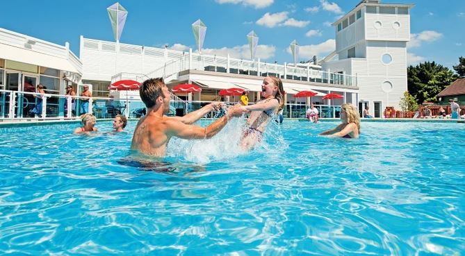 A dad playing in an outdoor pool at Rockley Park for pet friendly family holiday in Dorset