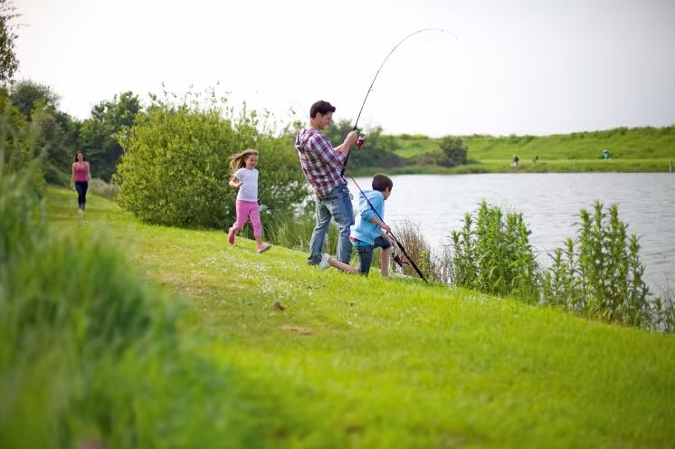 A family fishing at the side of a holiday park lake
