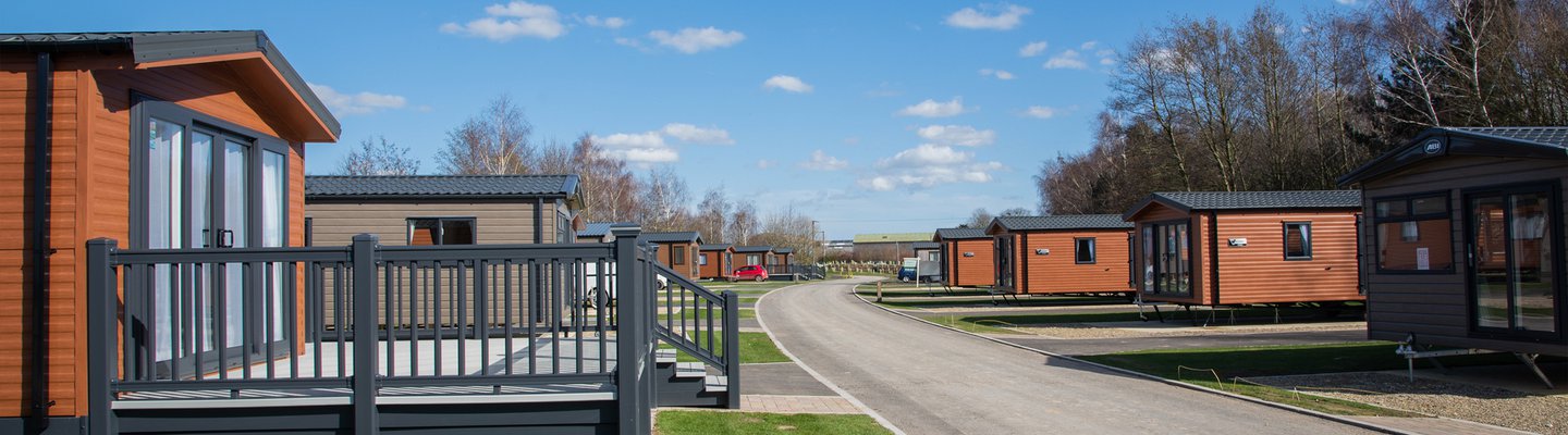 A wide street view of many holiday homes for sale on a holiday park