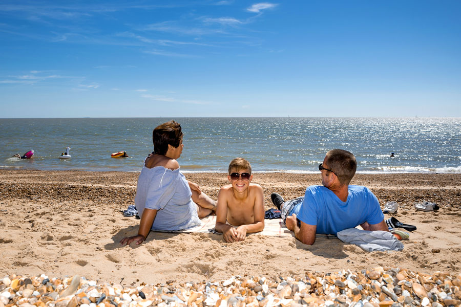 A family sitting on the beach on a bright sunny day