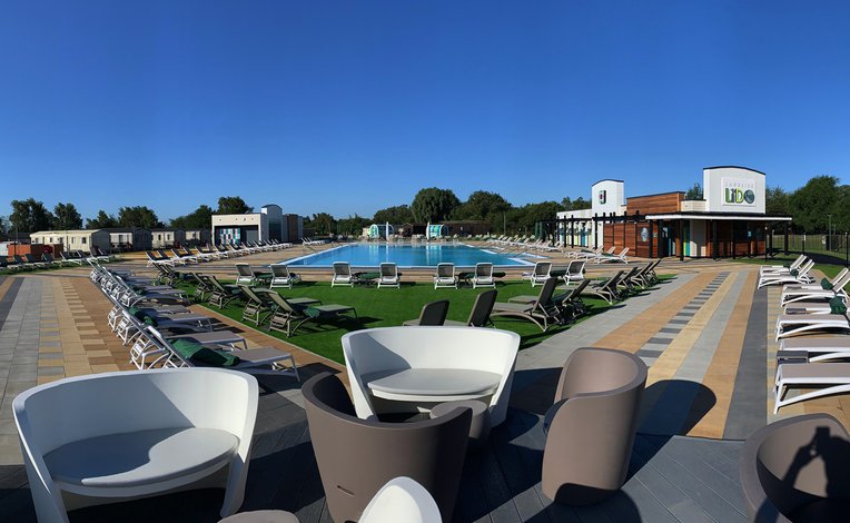 A view across an outdoor pool with great seating facilities and holiday homes nearby
