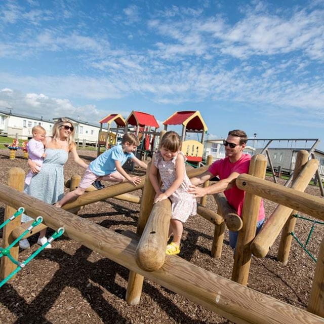 A family in a childrens play area on a holiday park on a warm sunny day