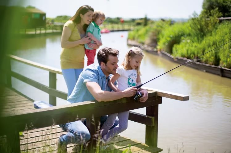 A family fishing at the side of a lake 