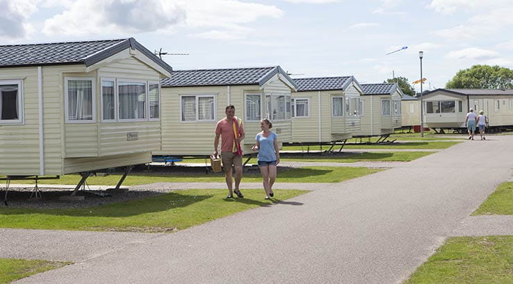 Two people walking towars the camera and two walking away surrounded by holiday homes