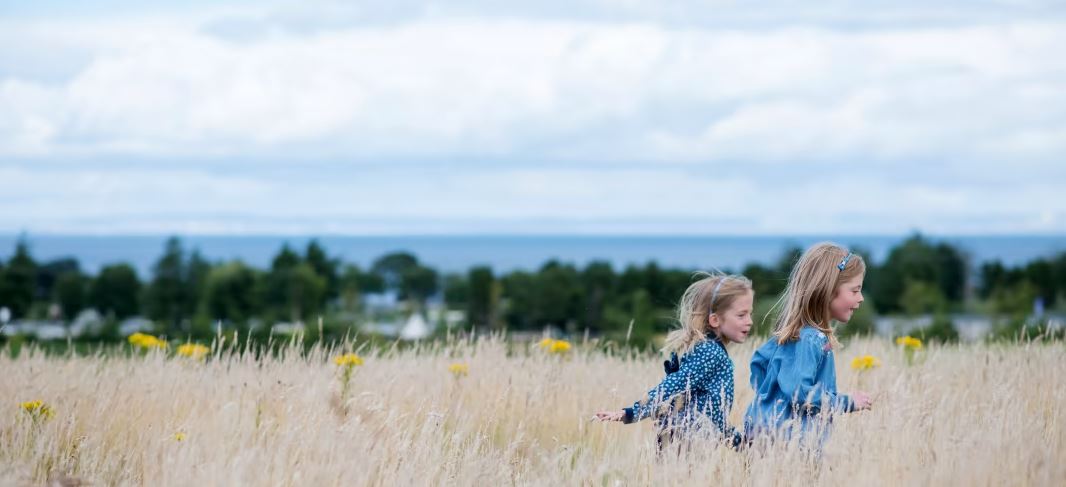 Two children running through long grass