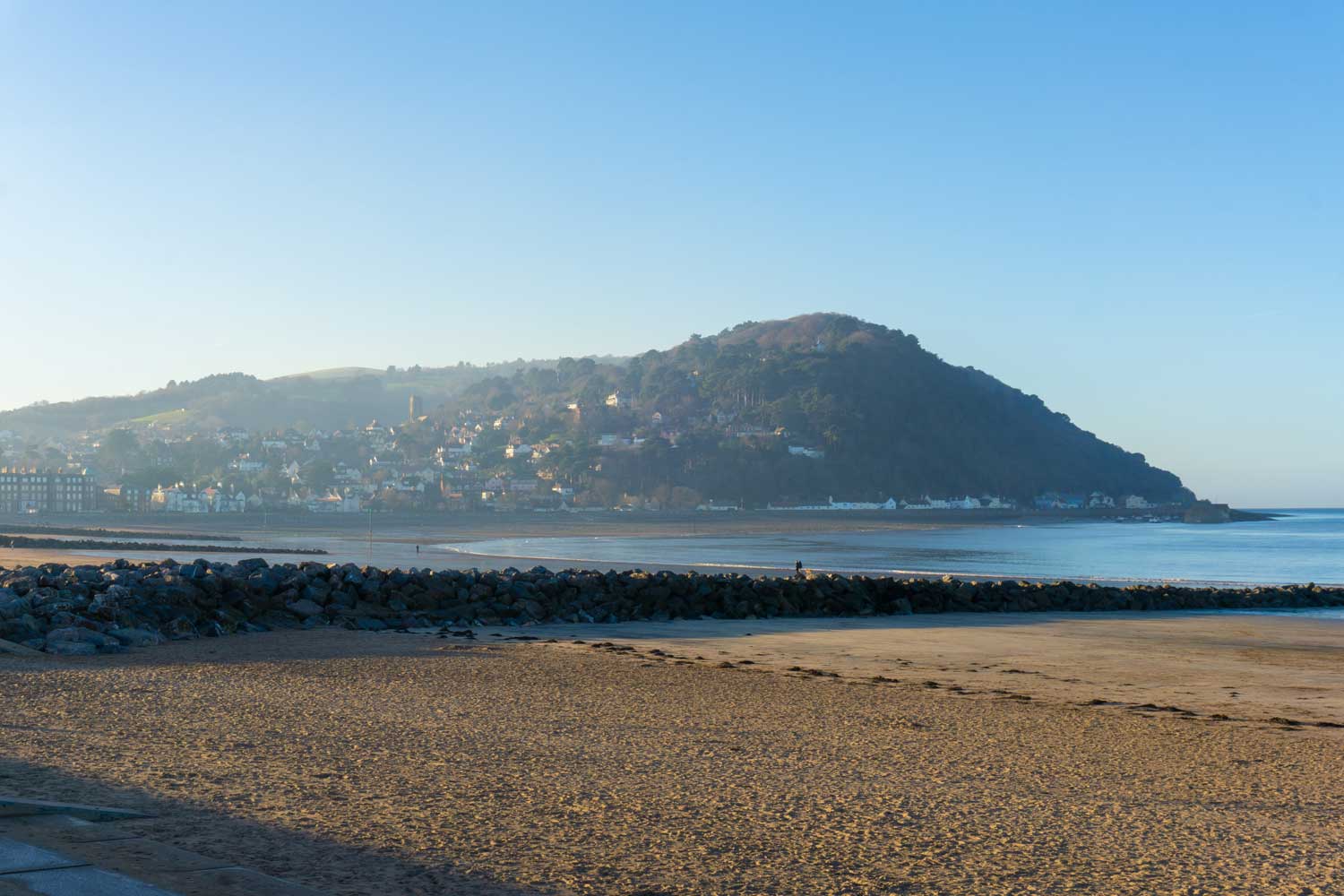 An Image of a Somerset Beach with a Local Town set against a Wooded Hill