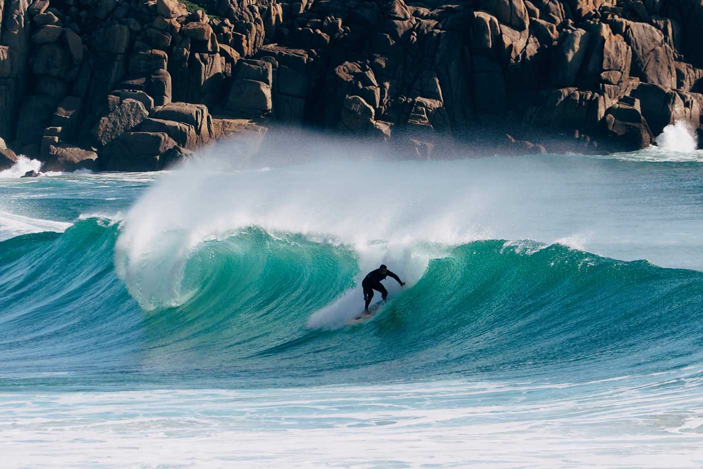A Lone Surfer Riding a Wave on a Cornish Beach