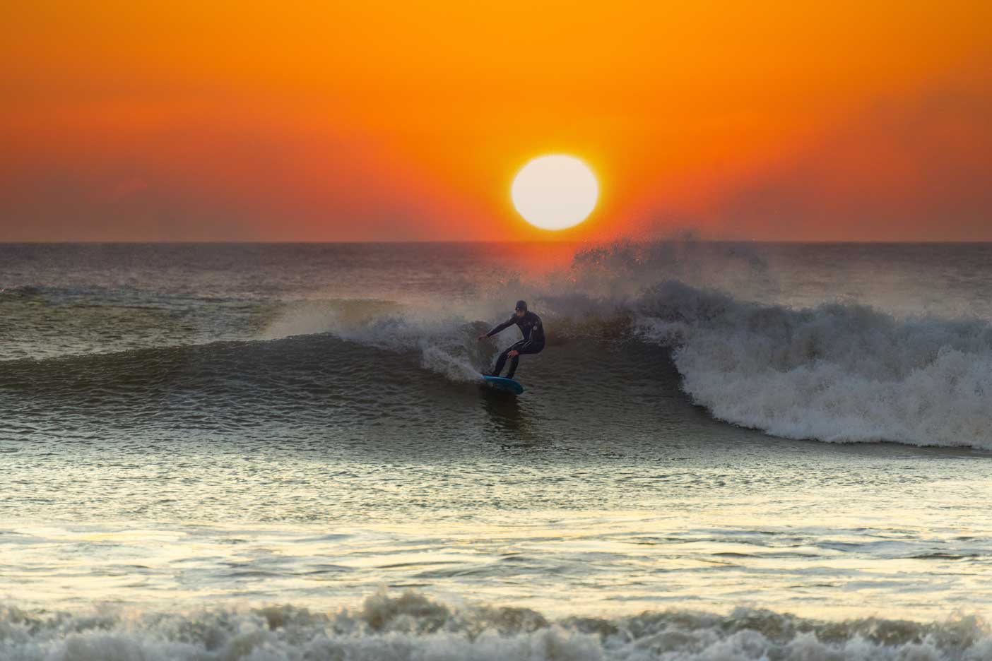A Lone Surfer Riding a Welsh Wave at Sunset