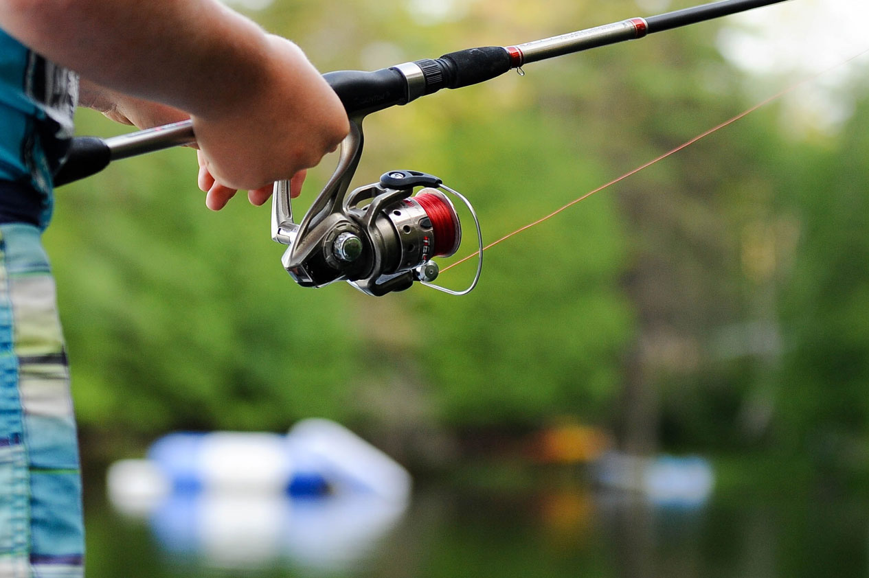 A Person Holding a Fishing Rod and Reel at the Lakeside