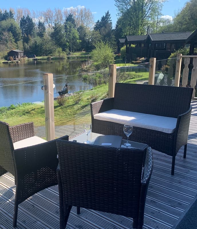 A View of a Person Fishing at a Lakeside taken from a Holiday Home Decking Area