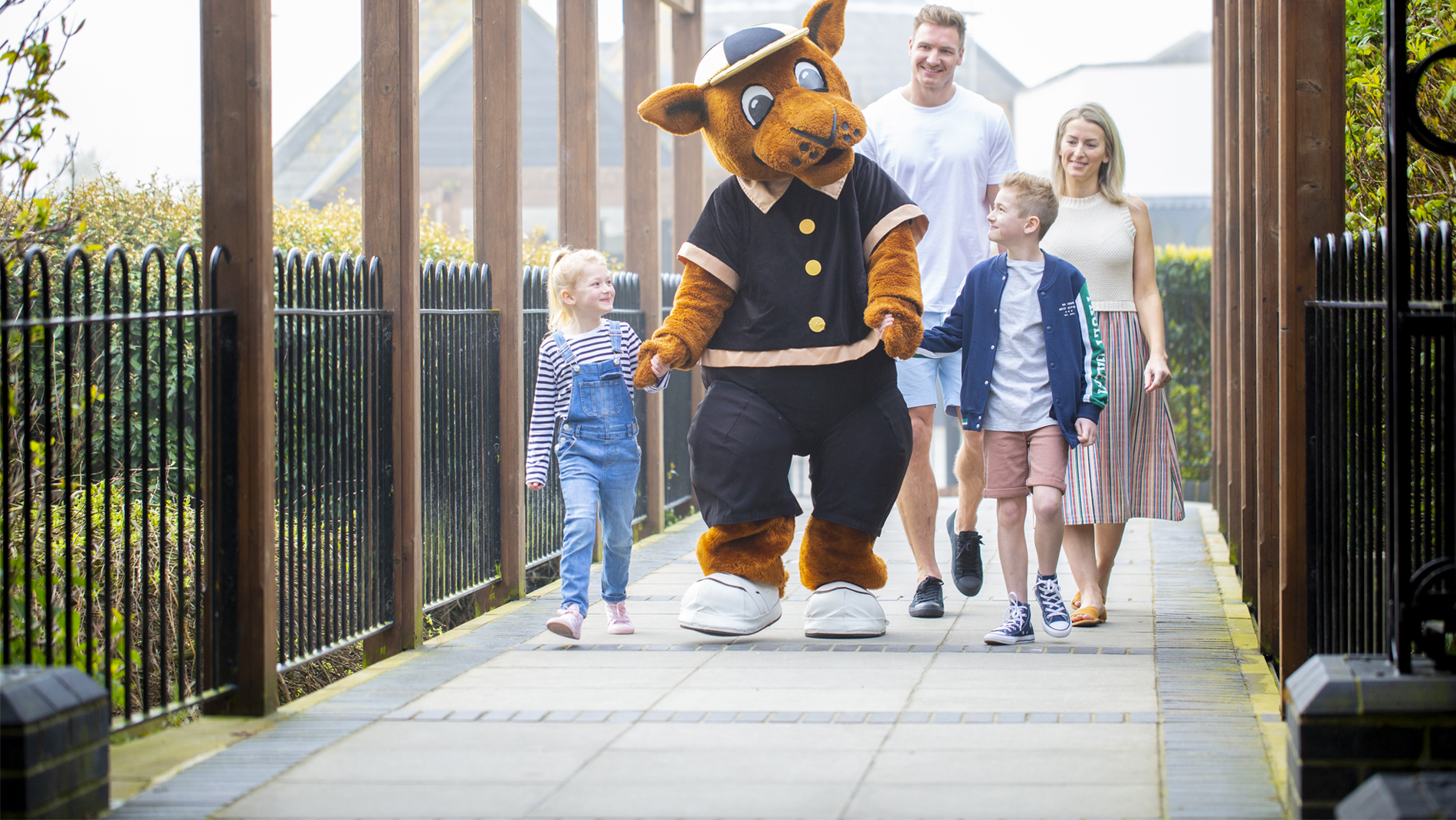 A Family Walking Along a Path with a Mascot for the Holiday Park