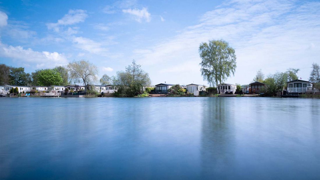 An Image of Holiday Homes next to the Lake on a Bright Sunny Day