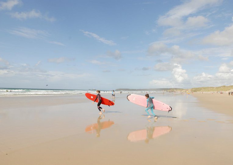 People Heading to the Surf on a Beach near St Ives Bay Holiday Park
