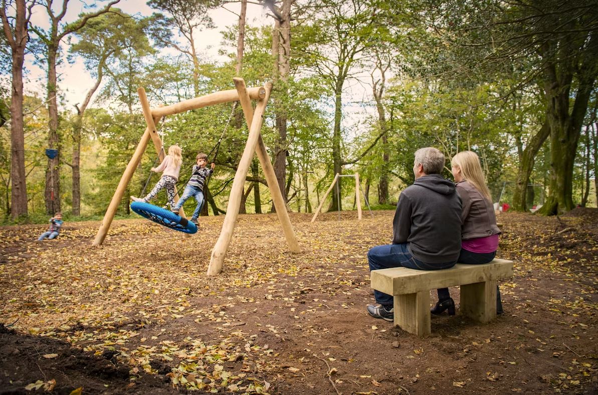 A Family playing on a Adventure Play Ground in the Woodland on a Holiday Park in Cornwall