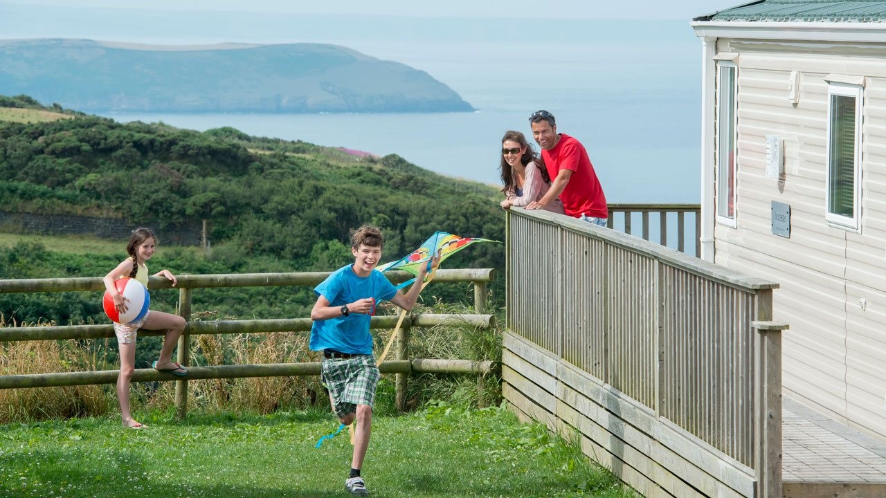 A Family Watching a Older Child Running with a Kite near to their Holiday Home with Far Reaching Sea Views in the Distance