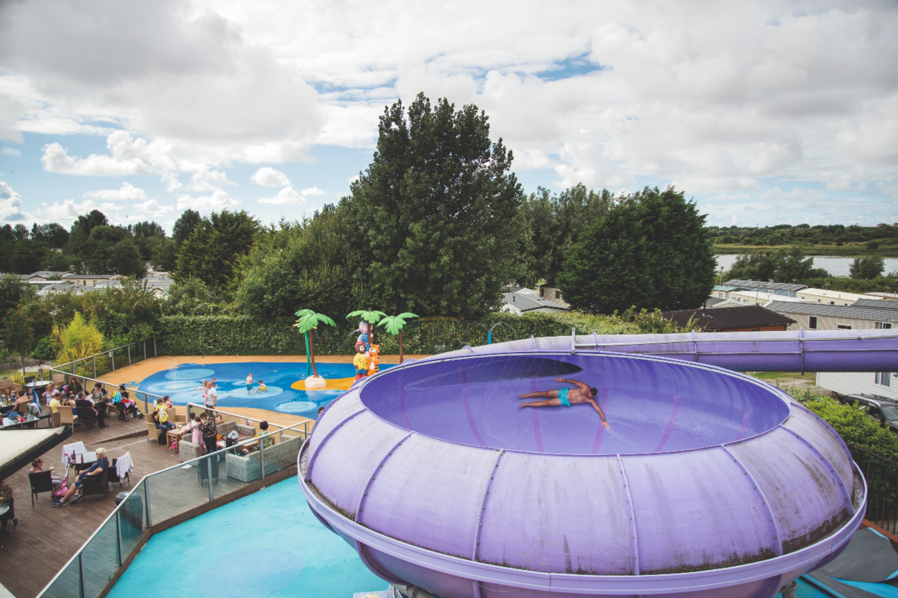 A Person Riding a Flume Ride on a Holiday Park in Blackpool with Other People Around the Pool