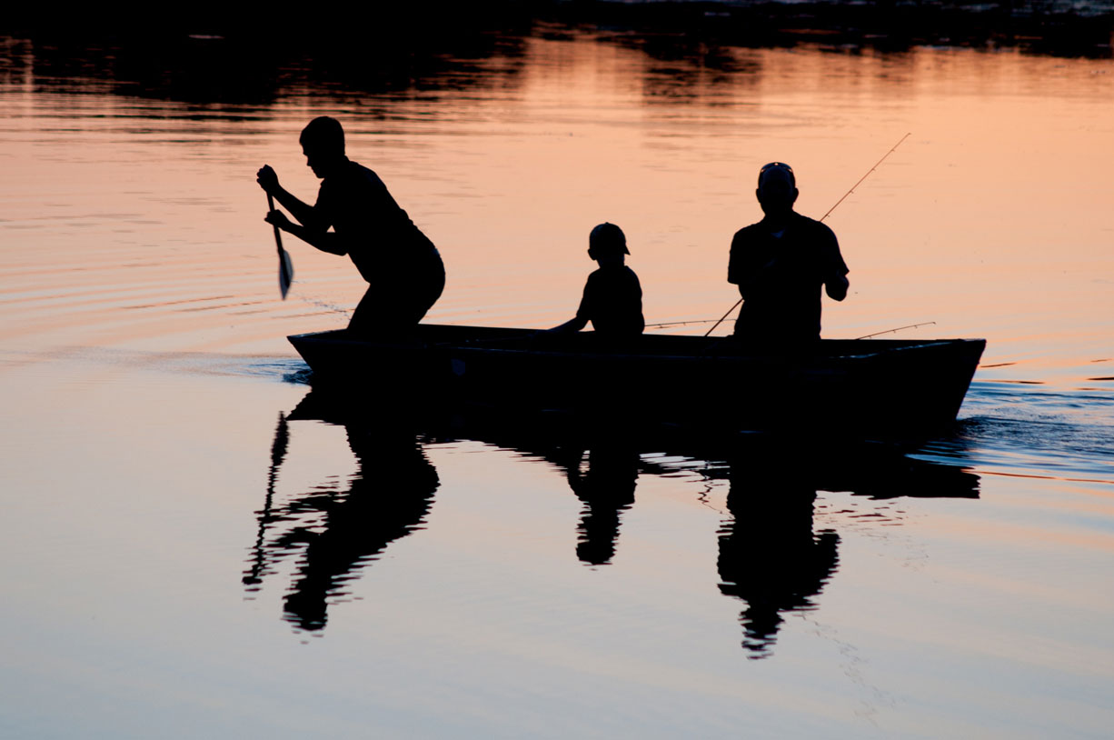 Three People in a Boat Silhouetted on a Lake