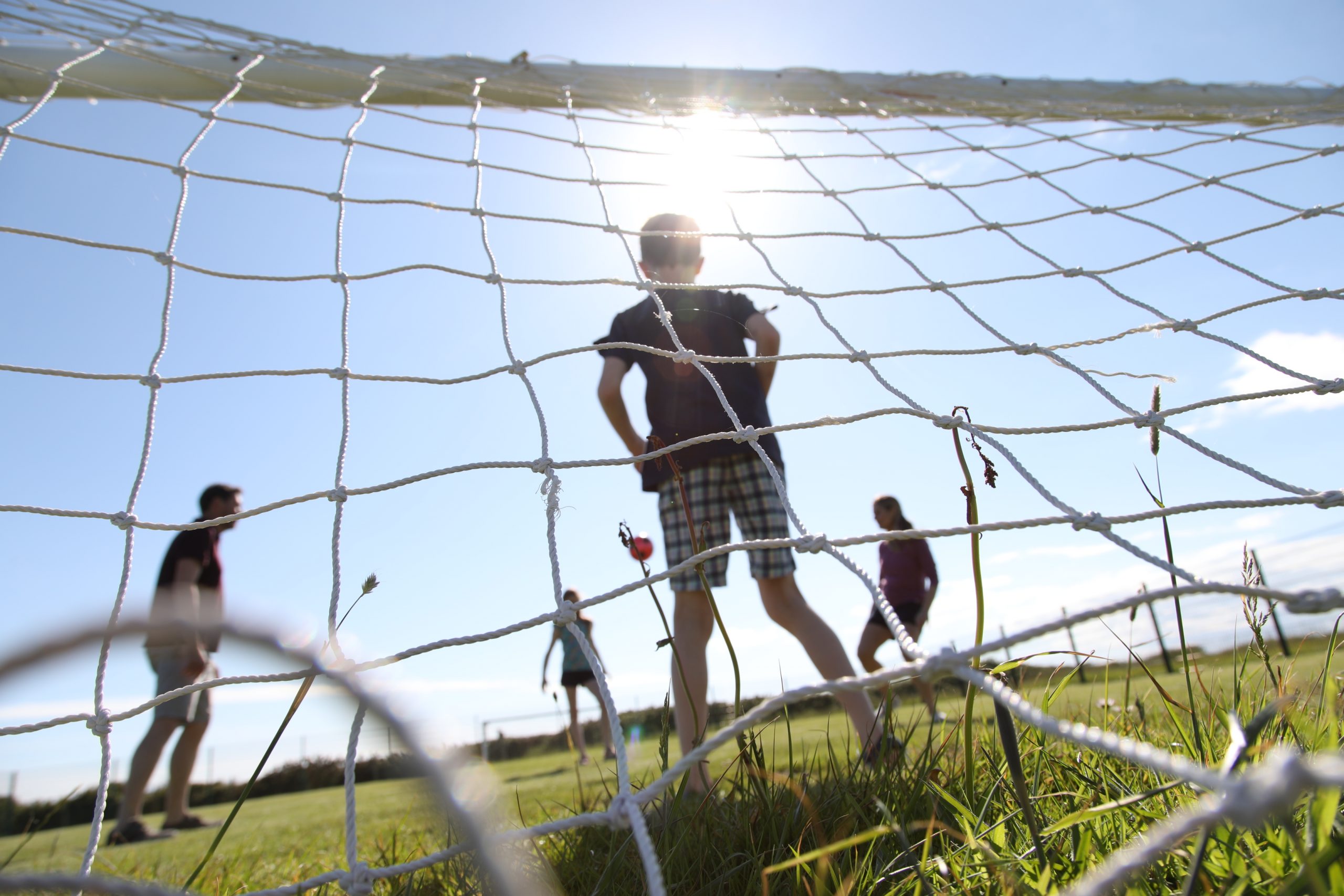 A Group of People Playing Football Behind a Goal Net