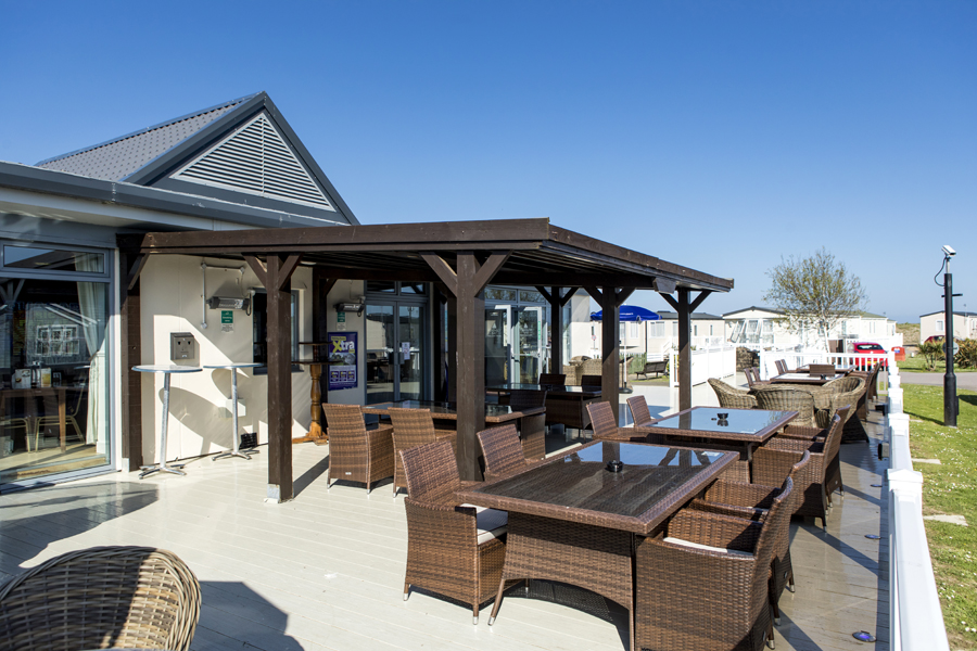 A Bar and Outdoor Seating Area with Tables and Chairs Surrounded by Lodges