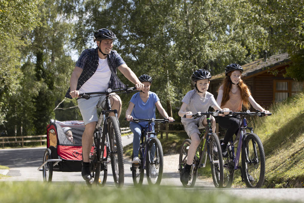 A Family Riding Bikes Along a Lane Through Forests and Woodland on a Weymouth Holiday Park