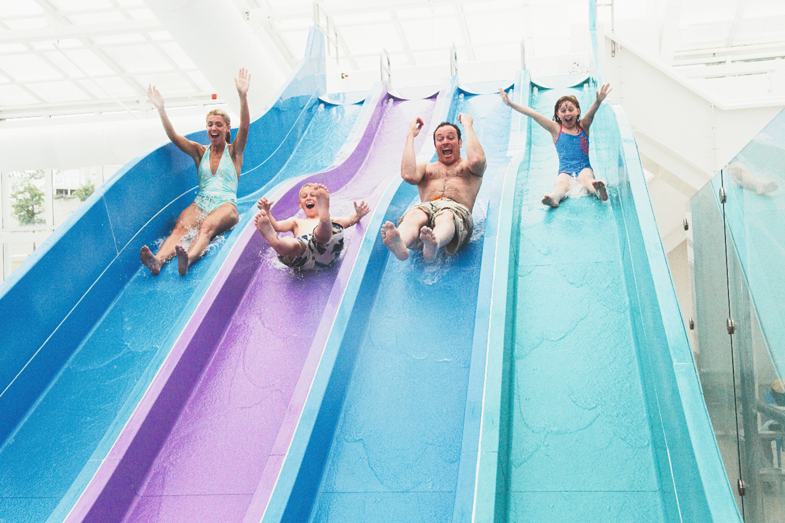 Four People Sliding down a Multi Coloured Four Laned Water Slide