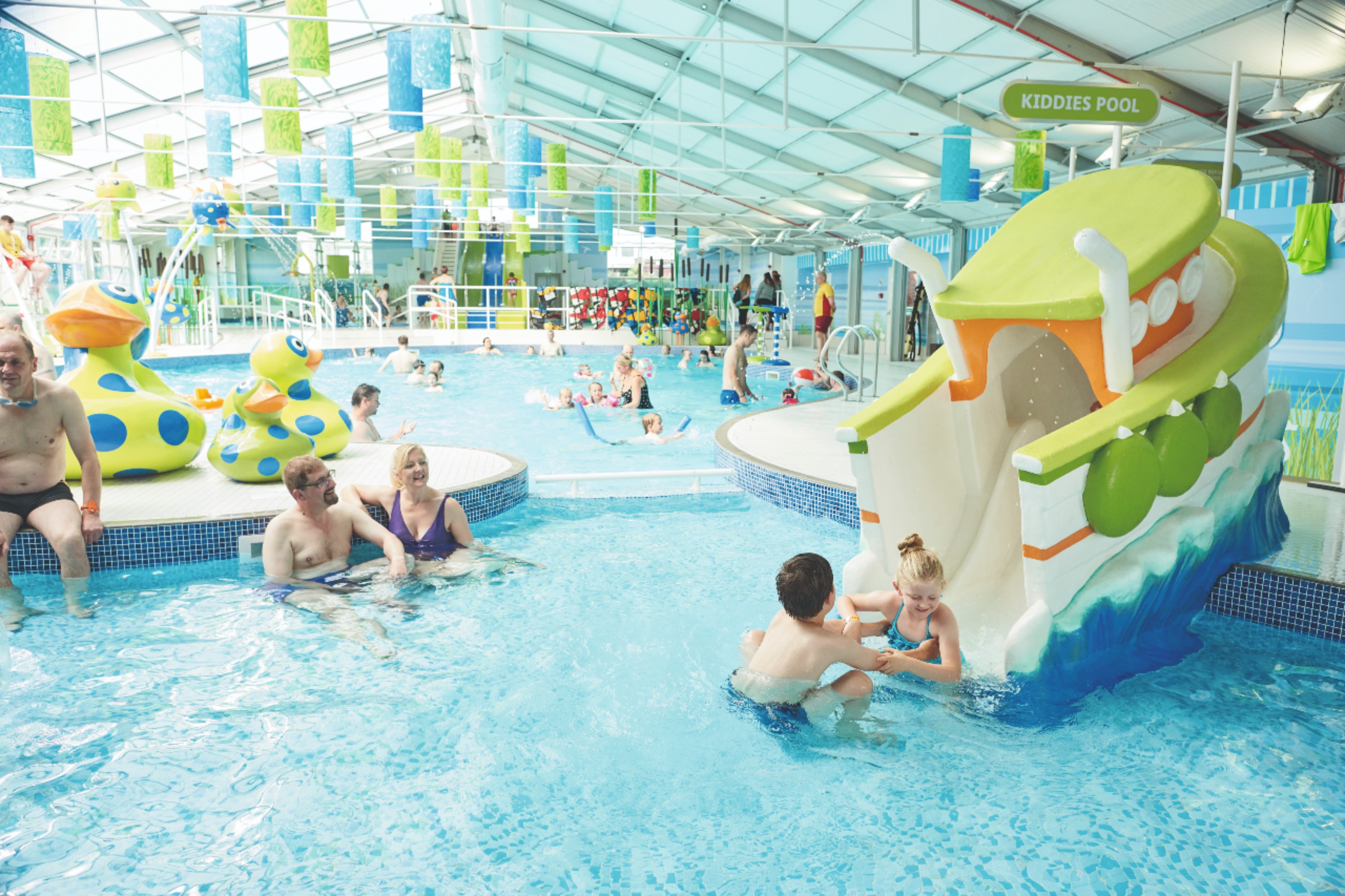 Lots of People Enjoying a Brightly Coloured Indoor Swimming Pool