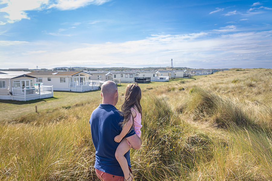 Two People Looking Towards Caravan Holiday Homes from The Nearby Sand Dunes