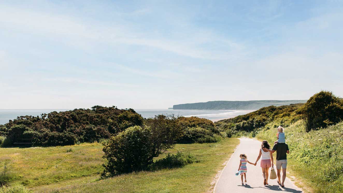 People walking along a path down towards the Sea