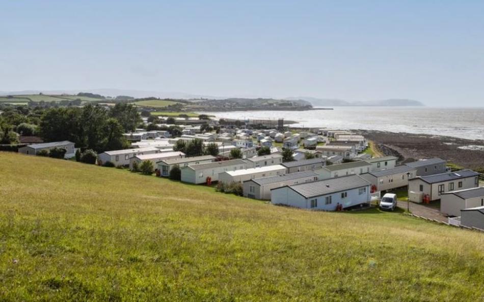 A view of holiday homes from the green field above with the ocean in the backgound