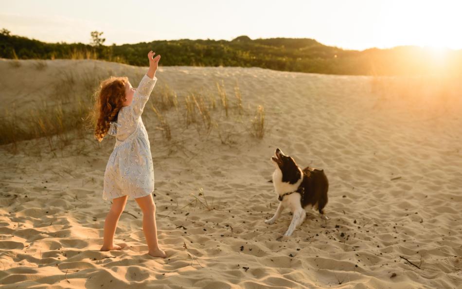 A girl playing with her dog in the sand dunes