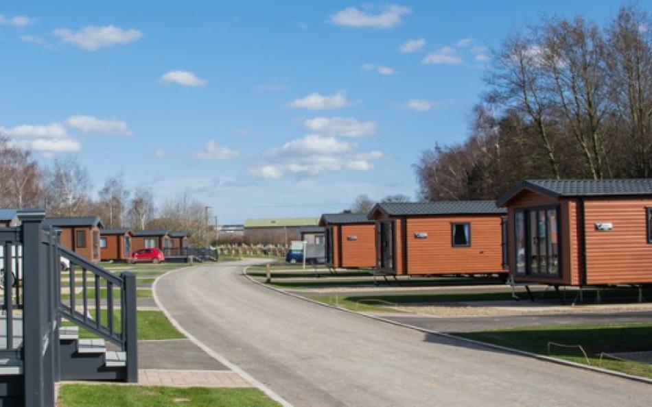 A wide street view of many holiday homes for sale on a holiday park