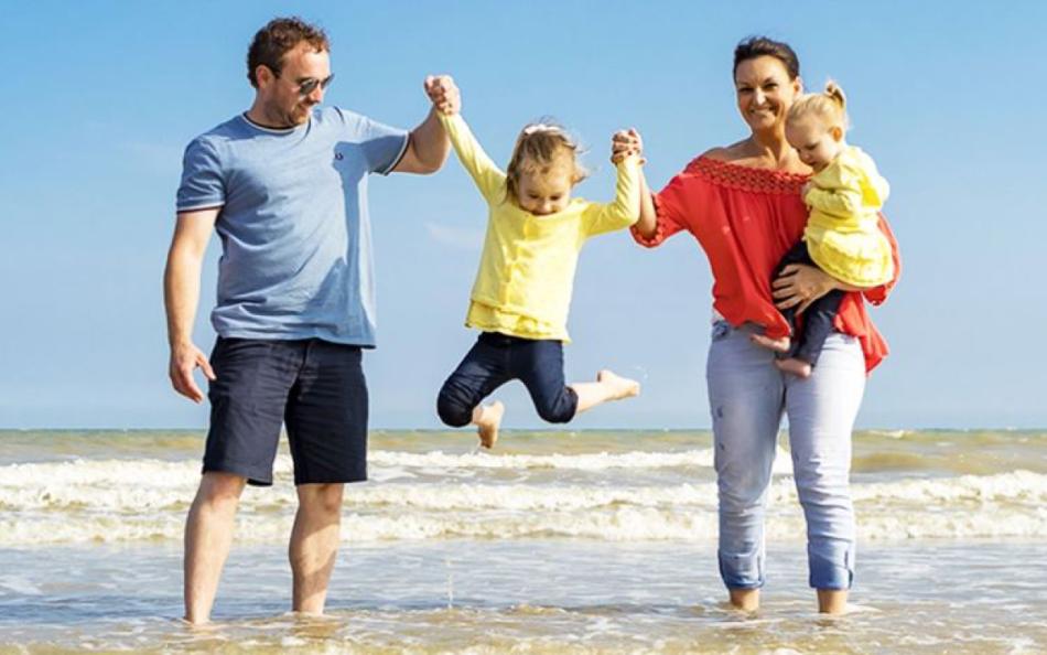 A family walking in the sea lifting their children up