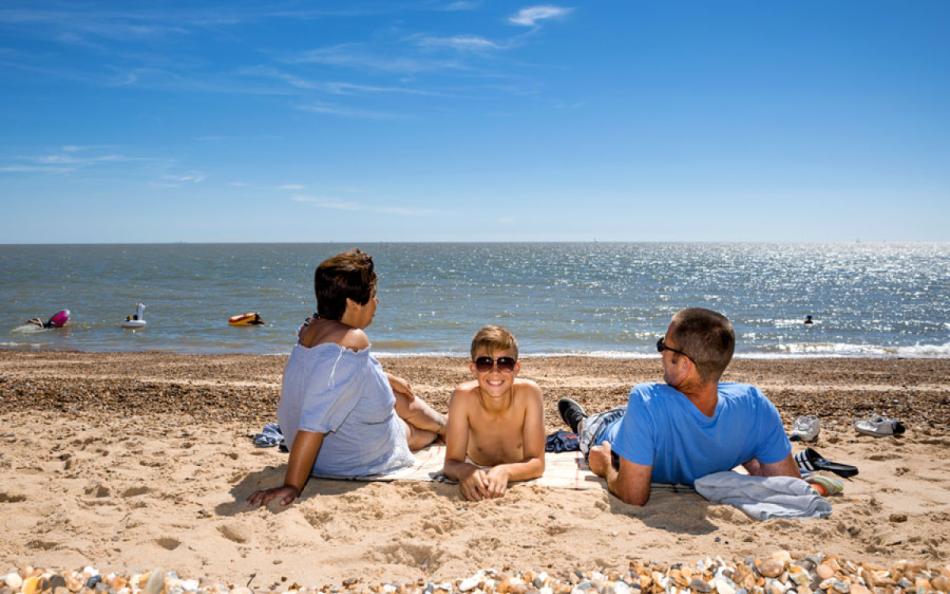 A family sitting on the beach on a bright sunny day