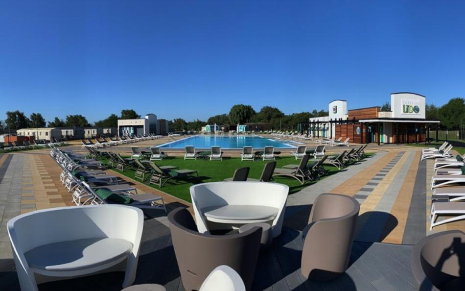 A view across an outdoor pool with great seating facilities and holiday homes nearby