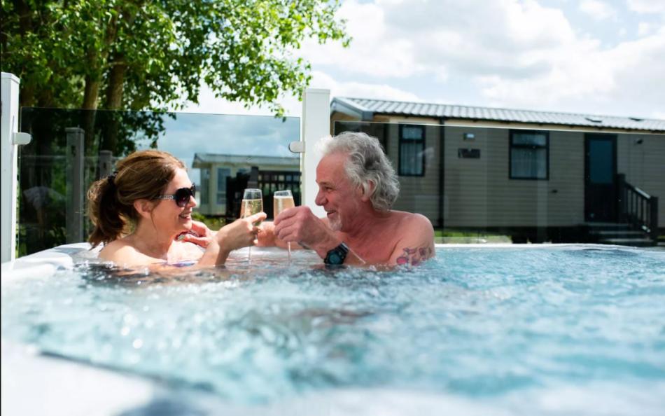 A couple enjoying a glass of champagne in their jacuzzi outside their holiday home