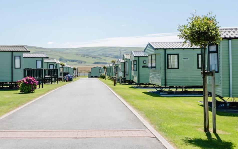 A road of holiday homes with beautifully cared for grass and mountains in the distance