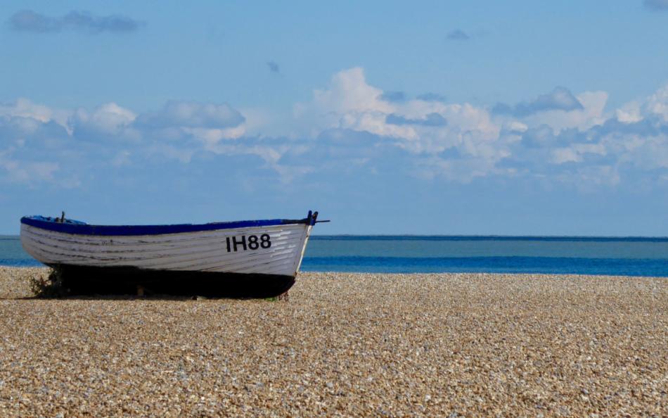 A boat on the shoreline with blue sky and sea