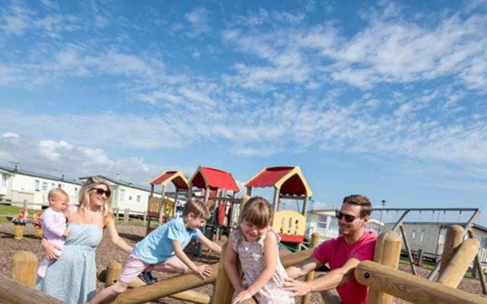 A family in a childrens play area on a holiday park on a warm sunny day
