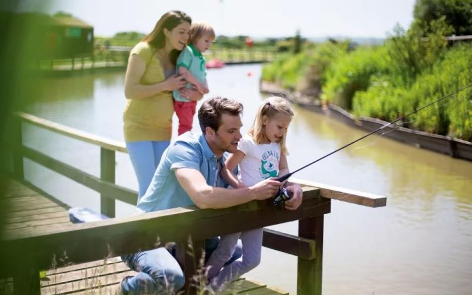 A family fishing at the side of a lake 