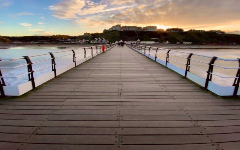 An image of a pier out in the sea looking back to land