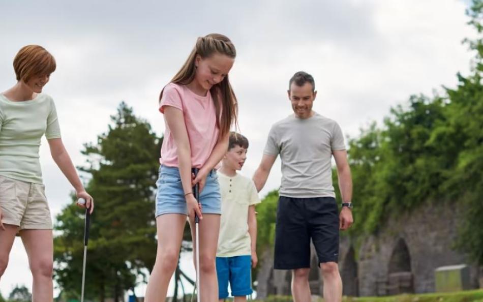 A family enjoying a game of golf at Kiln Park by Tenby beach