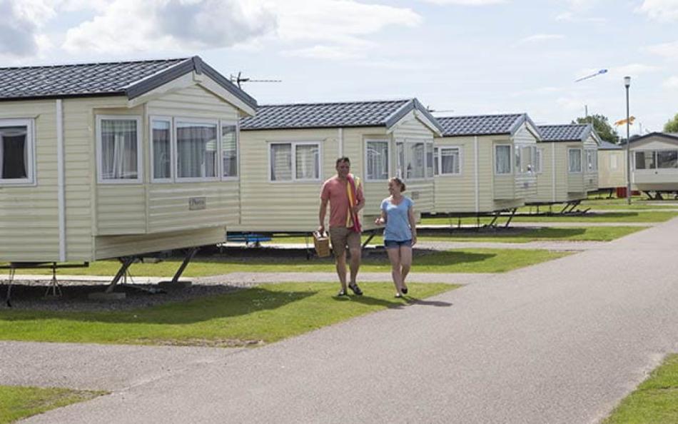 Two people walking towars the camera and two walking away surrounded by holiday homes