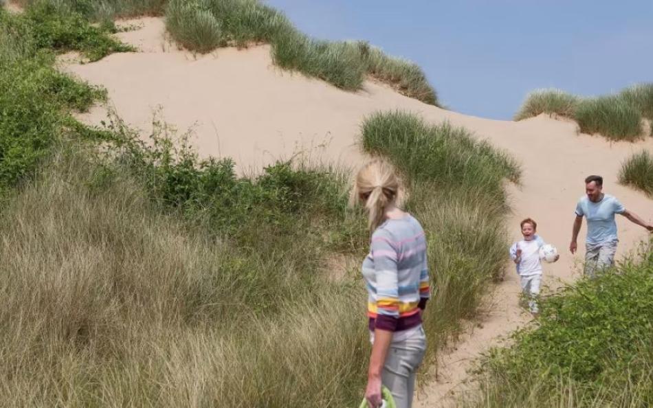 A family walking through sands dunes on a bright and warm summers day