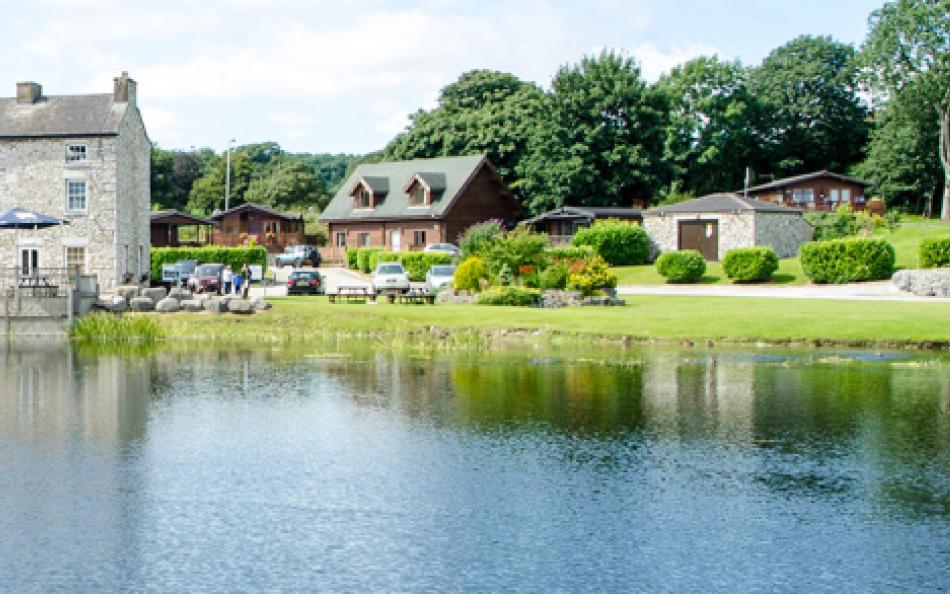 An image of a holiday park with a lake in the foreground