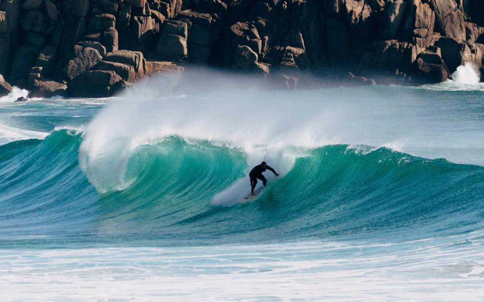 A Lone Surfer Riding a Wave on a Cornish Beach