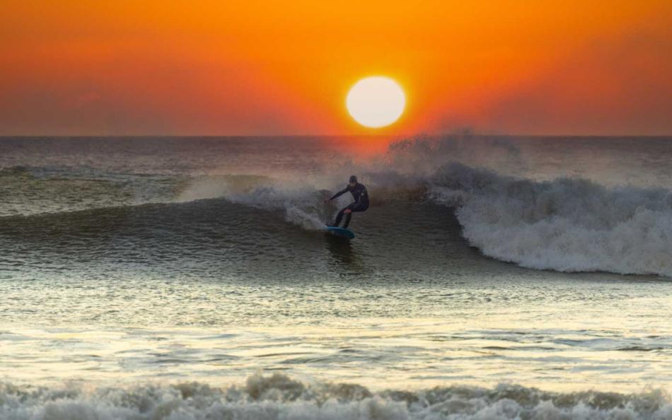 A Lone Surfer Riding a Welsh Wave at Sunset